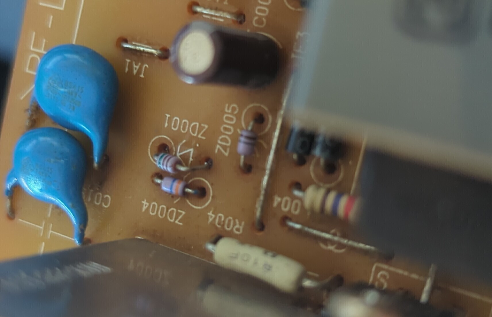 A brown PCB with a small diode partially sticking up from where it was previously soldered to.