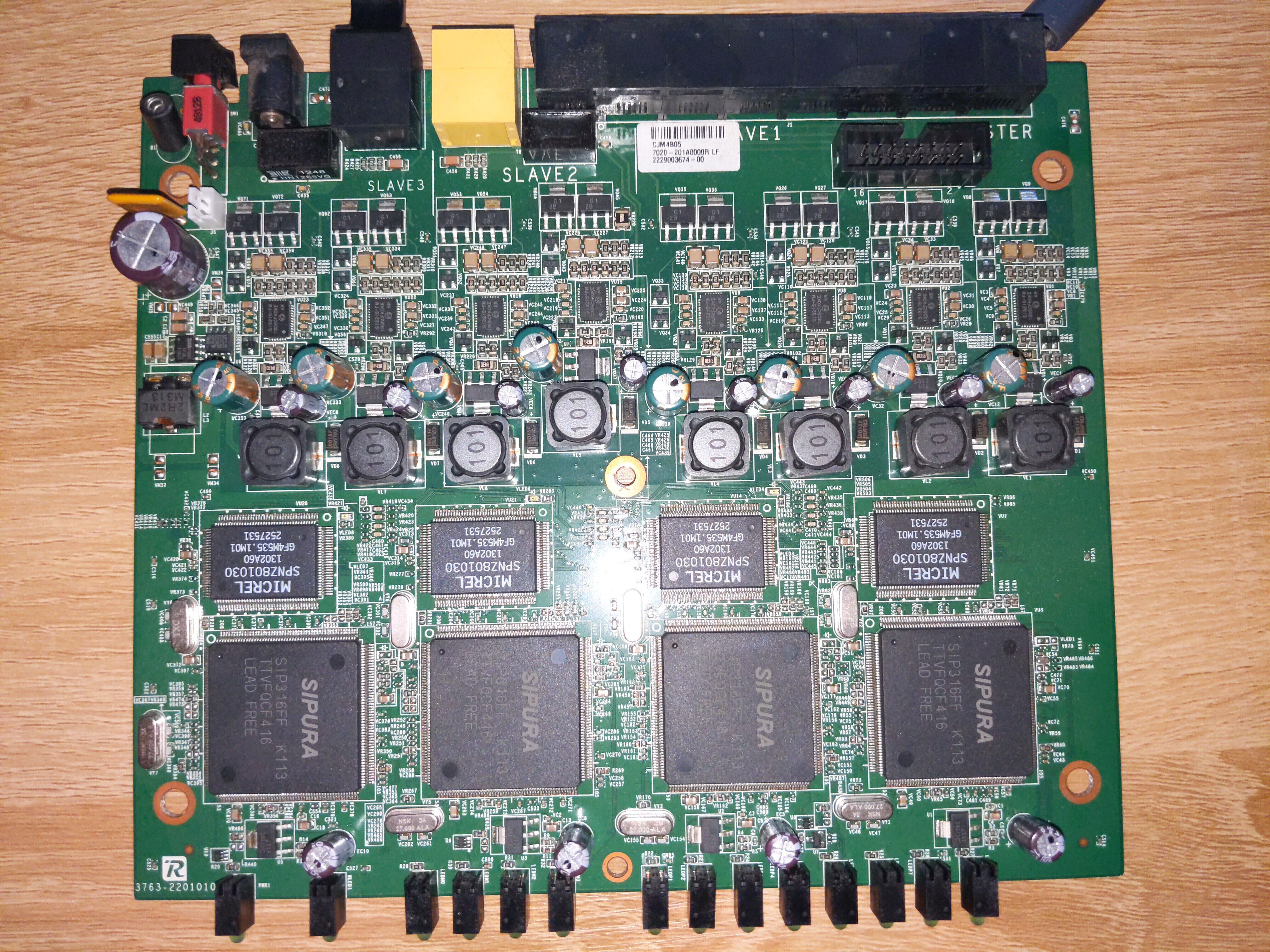 A photo of the SPA8000's system board, showing four "pillars" going from the front of the board to the rear, all made up of the same sets of components. Each has one big chip down the bottom, a medium sized on above, and then a bunch of analogue components towards the rear, nearer to the phone ports.